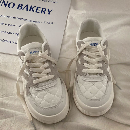 Weiße Sneaker mit grauen Details, gestepptem Muster, Schnürsenkeln, auf weißem Hintergrund.