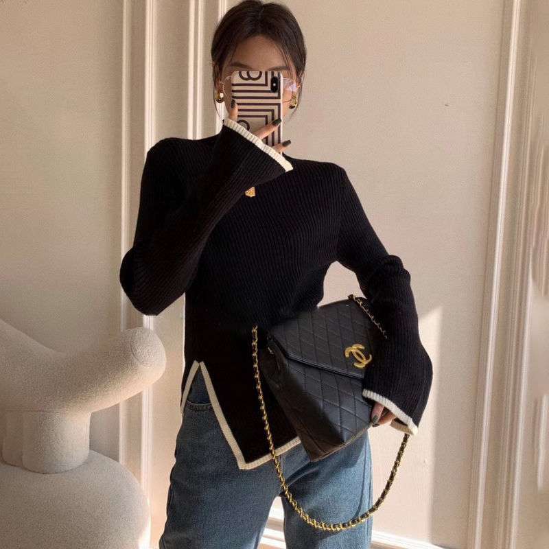 Frau mit schwarzem Pullover, blauer Jeans, Chanel-Tasche, Smartphone, modernes Interieur.