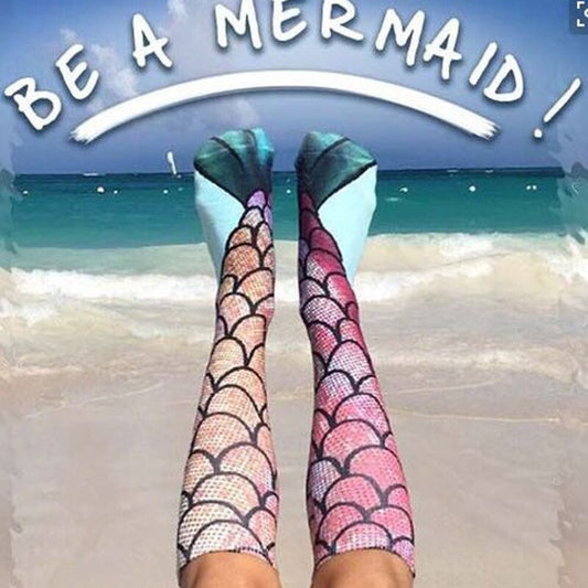 Meerjungfrau-Socken am Strand, buntes Schuppenmuster, inspirierender Text, Ozeanhintergrund.