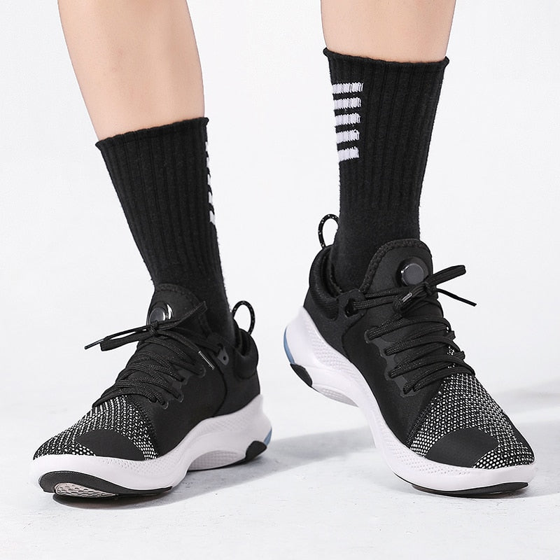 Schwarze Sportschuhe mit weißer Sohle, gestricktes Obermaterial, ideal für Laufen und Fitness.