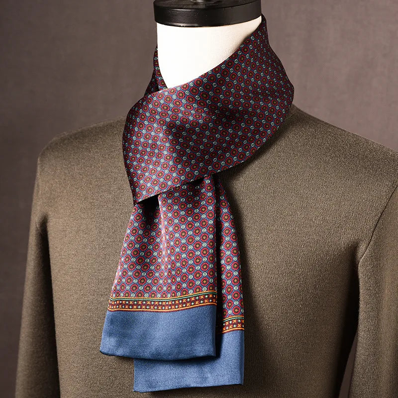 Seidenschal mit kleinem rot-blauem Blütenmuster und blauer Kante, locker um eine Büste mit olivgrünem Pullover geschlungen. 1