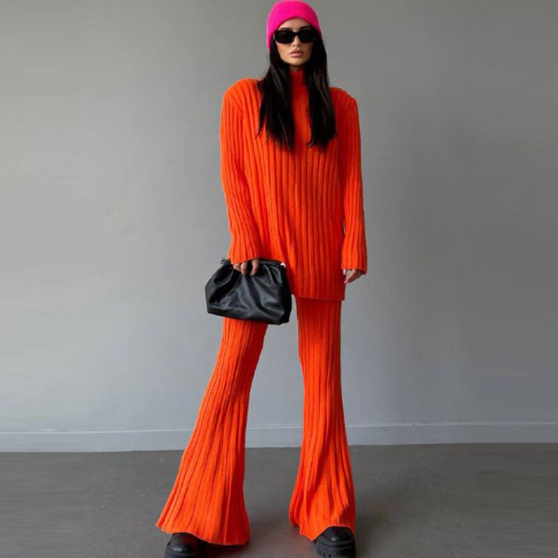 Frau in orangefarbenem Strickanzug mit pinker Mütze und schwarzer Tasche, modisch, modern.