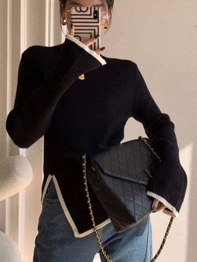 Frau mit schwarzem Strickpullover, blauer Jeans und schwarzer gesteppter Umhängetasche.