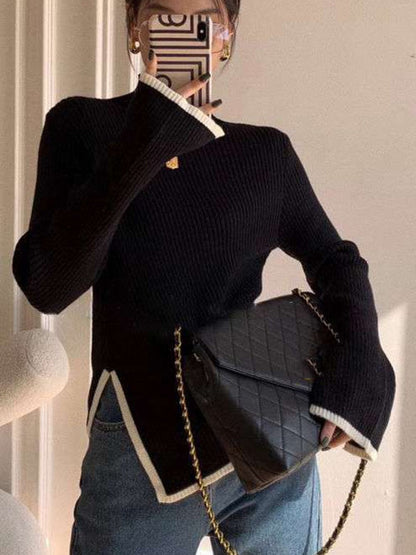 Frau mit schwarzem Strickpullover, blauer Jeans und schwarzer gesteppter Umhängetasche.