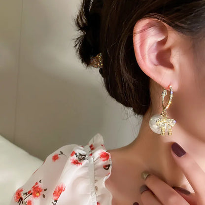 Frau mit goldenen Ohrringen und Perlenanhänger, florale Bluse, eleganter Schmuck, Nahaufnahme.