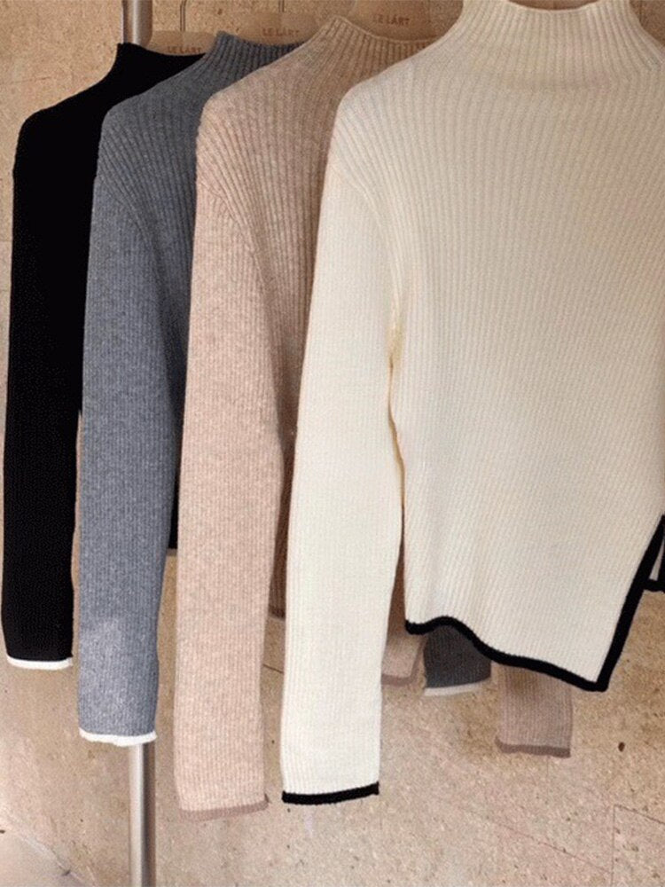 Vier Rollkragenpullover in Schwarz, Grau, Beige und Weiß aus Strickstoff auf Kleiderstange.