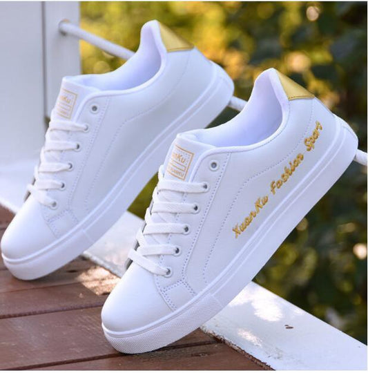 Weiße Sneaker mit goldenen Akzenten, modisch, sportlich, für Herren, auf Holzuntergrund.