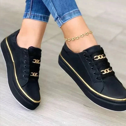 Schwarze Damen-Sneaker mit goldenen Ketten, Freizeitschuhe, modisch, bequem, Jeanshintergrund.