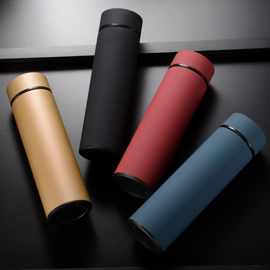 Vier Thermosflaschen in Schwarz, Rot, Blau und Gold auf schwarzem Hintergrund.