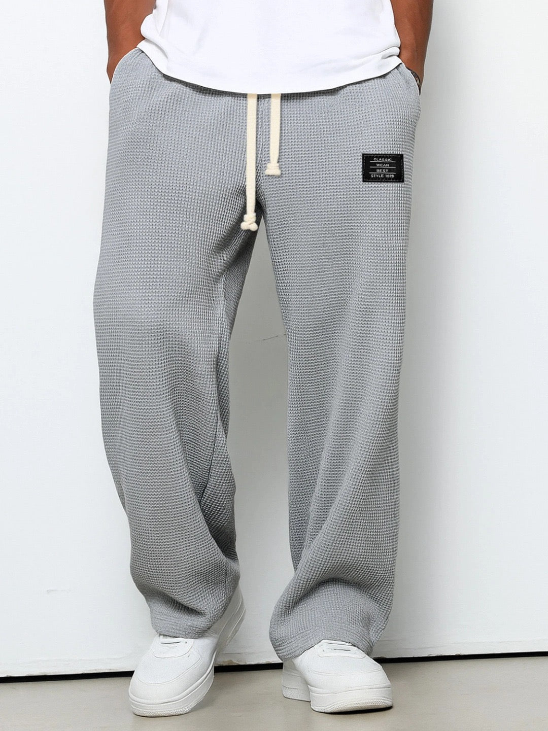Waffelstrickhose in mittlerem Grau mit weitem Bein, am Model mit weißem Shirt und Sneakern, Frontansicht. 3