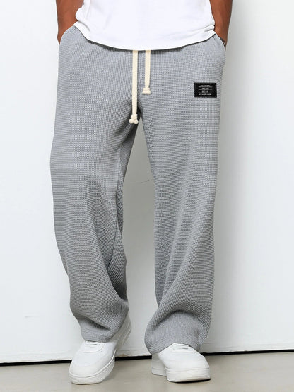 Waffelstrickhose in mittlerem Grau mit weitem Bein, am Model mit weißem Shirt und Sneakern, Frontansicht. 3