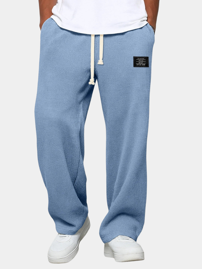 Waffelstrickhose in Hellblau, frontal getragen mit weißem T-Shirt und weißen Sneakern, Kordel mit Knoten am Bund. 4