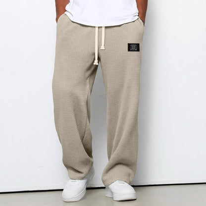 Waffelstrickhose in Beige, Frontansicht am Model mit weißem T-Shirt und Sneakern, Hände in den Taschen. 6