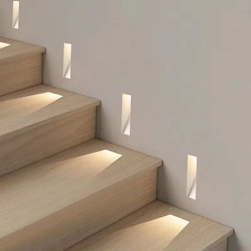Mehrere schmale Einbauleuchten in der Wand beleuchten die Holzstufen einer Treppe 6