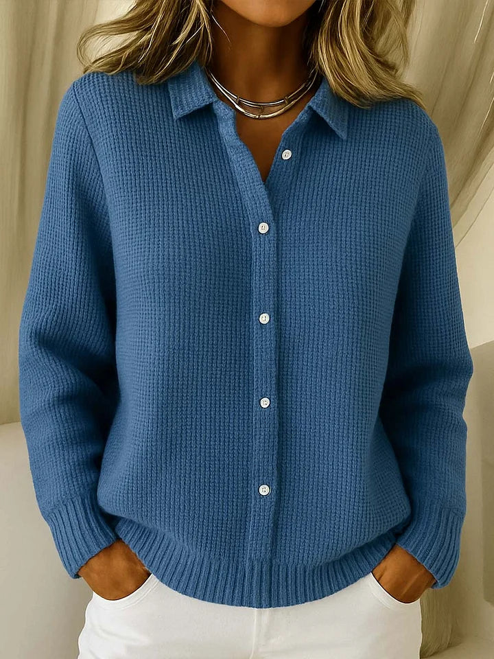Frontansicht des Strickpullovers in kräftigem Blau am Model, mit Kragen, Knopfleiste und strukturiertem Strickmuster, kombiniert mit weißer Hose. 4
