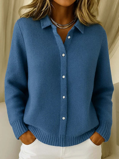 Frontansicht des Strickpullovers in kräftigem Blau am Model, mit Kragen, Knopfleiste und strukturiertem Strickmuster, kombiniert mit weißer Hose. 4