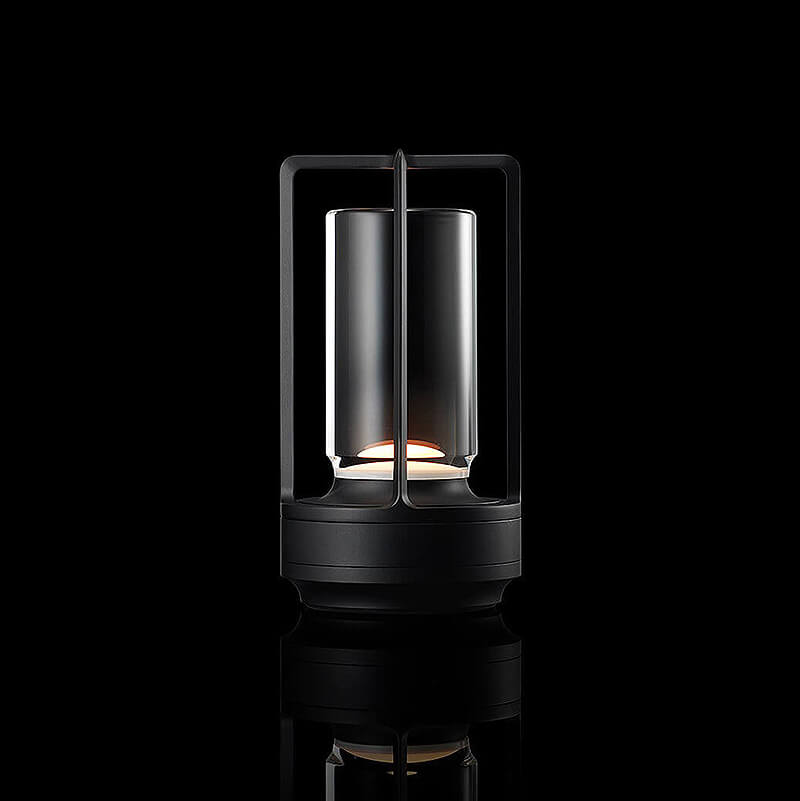 Studio-Aufnahme der leuchtenden Tischlampe in Schwarz mit Glaszylinder und offenem Rahmen vor schwarzem Hintergrund mit Spiegelung. 11