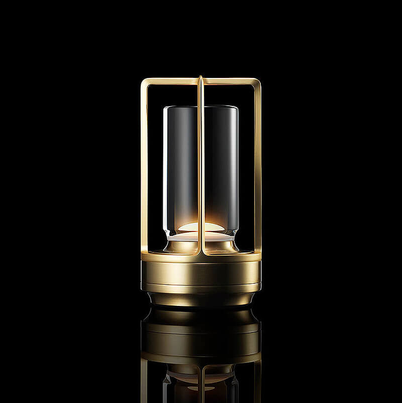 Studio-Aufnahme der leuchtenden Tischlampe in Messing-Optik mit offenem Rahmen und Glaszylinder vor schwarzem Hintergrund mit Spiegelung. 1