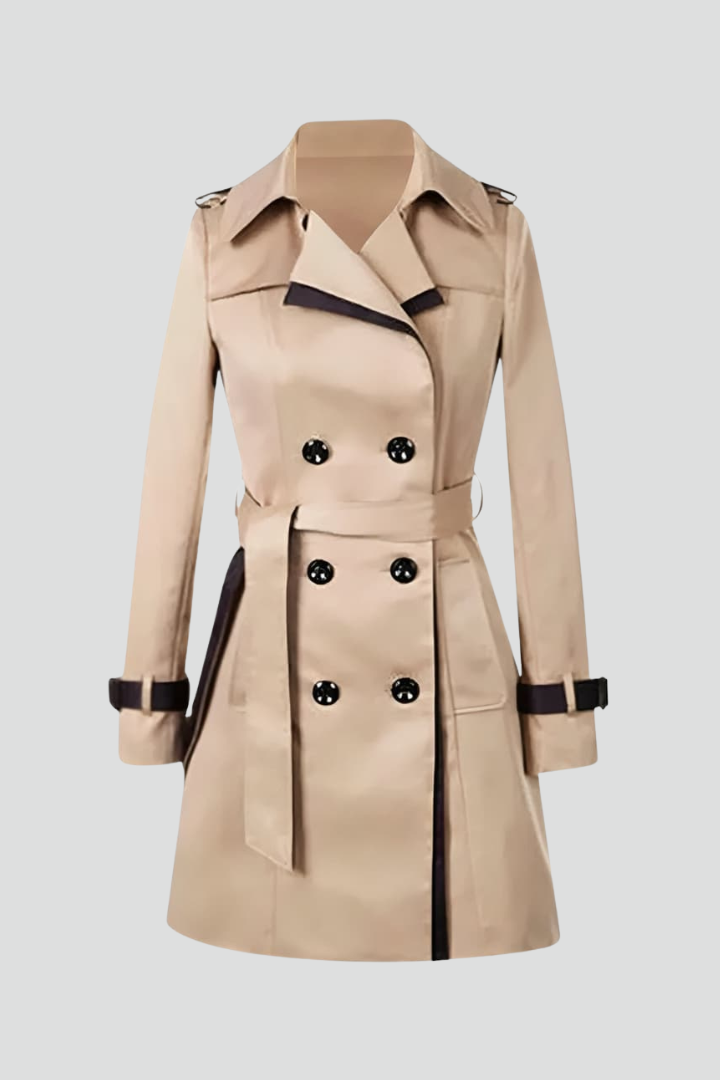 Beiger zweireihiger Trenchcoat mit dunklen Zierkanten, Bindegürtel und Ärmelriemen, frei gestellt auf hellem Hintergrund. 1