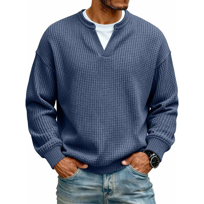 Pullover in dunklem Blau mit Waffelstruktur und V-Ausschnitt, am Model über weißem Shirt kombiniert mit Jeans. 7