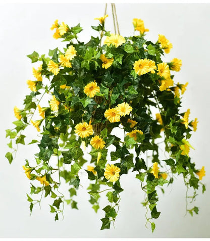 Gelbe Kunstblumen mit dichtem Efeulaub, als Hängekorb an Seilen aufgehängt, vor hellem Hintergrund. 2