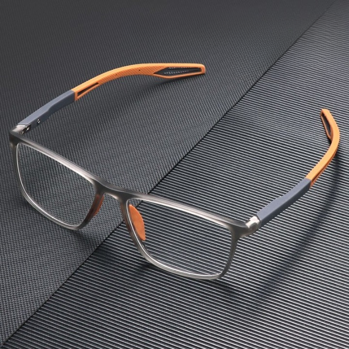 Brille mit grauem Rahmen und orangefarbenen Bügeln, aufgeklappt auf dunkler, gerillter Oberfläche 2