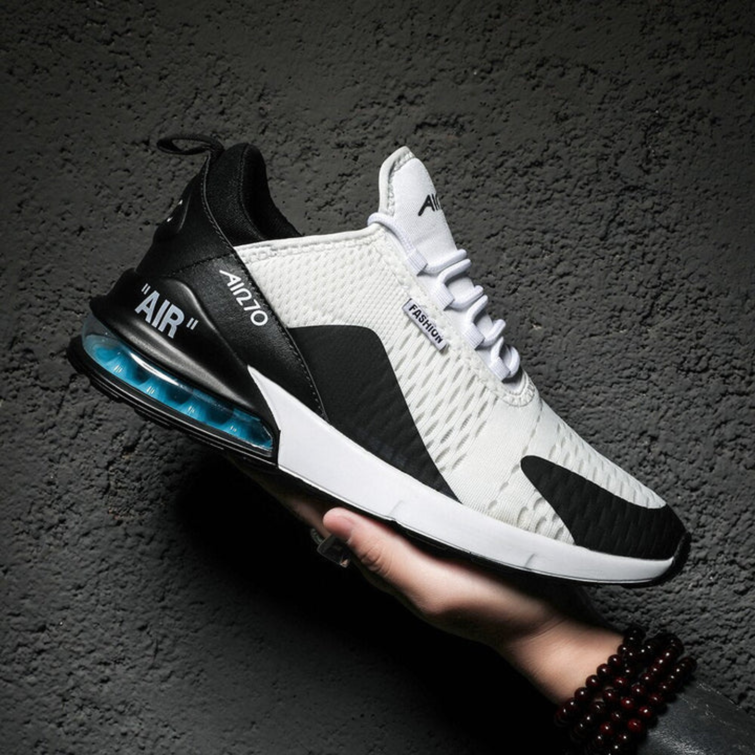 Weiße und schwarze Unisex-Sneaker mit Luftpolstersohle, modisches Design, auf grauem Hintergrund.