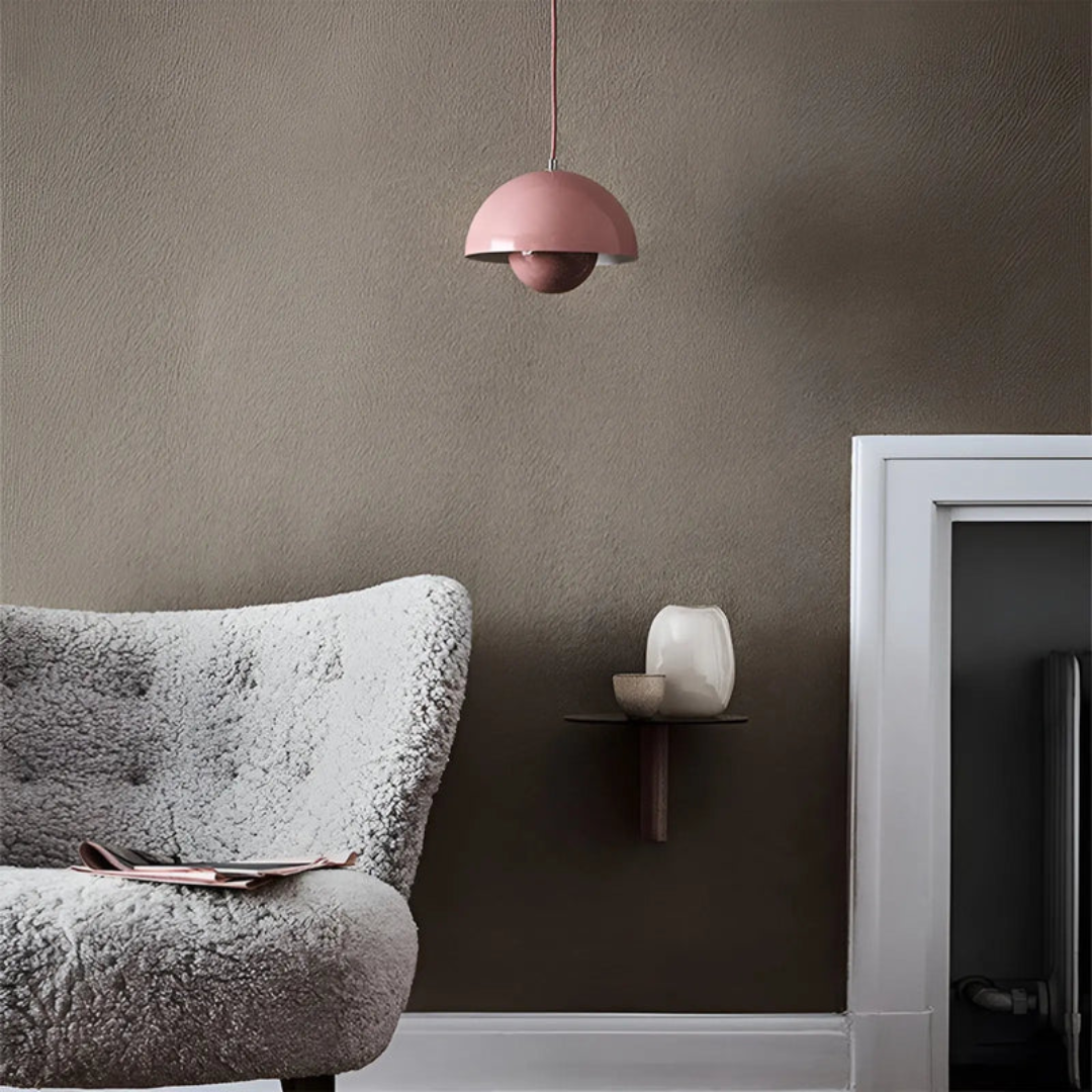 Rosa Pendelleuchte, modernes Design, über grauem Sessel, skandinavische Inneneinrichtung.