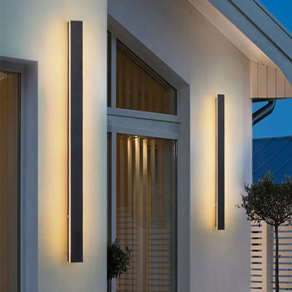 Moderne schwarze Außenwandleuchten, vertikal, beleuchtet, an weißer Hauswand montiert.
