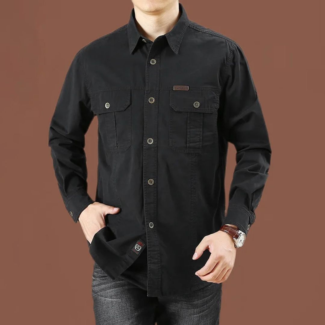 Mann in schwarzem Hemd mit Taschen, Jeans, brauner Hintergrund, Herrenmode, Freizeitkleidung.