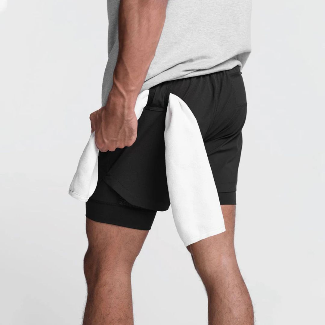 Mann in schwarzer Sporthose mit weißem Handtuch, Fitness, Training, Sportbekleidung.