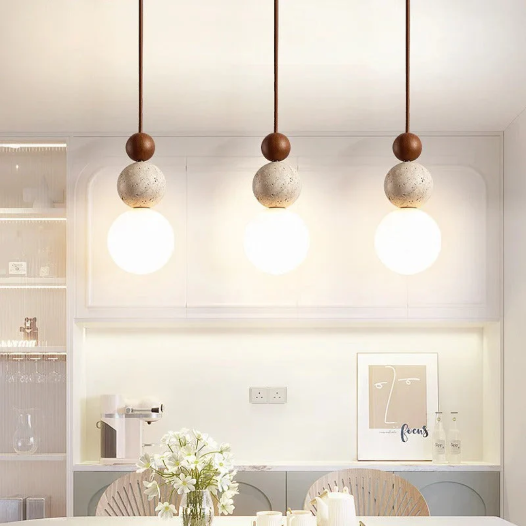 Drei moderne Pendelleuchten aus Holz und Beton über einem Esstisch in minimalistischem Raum.