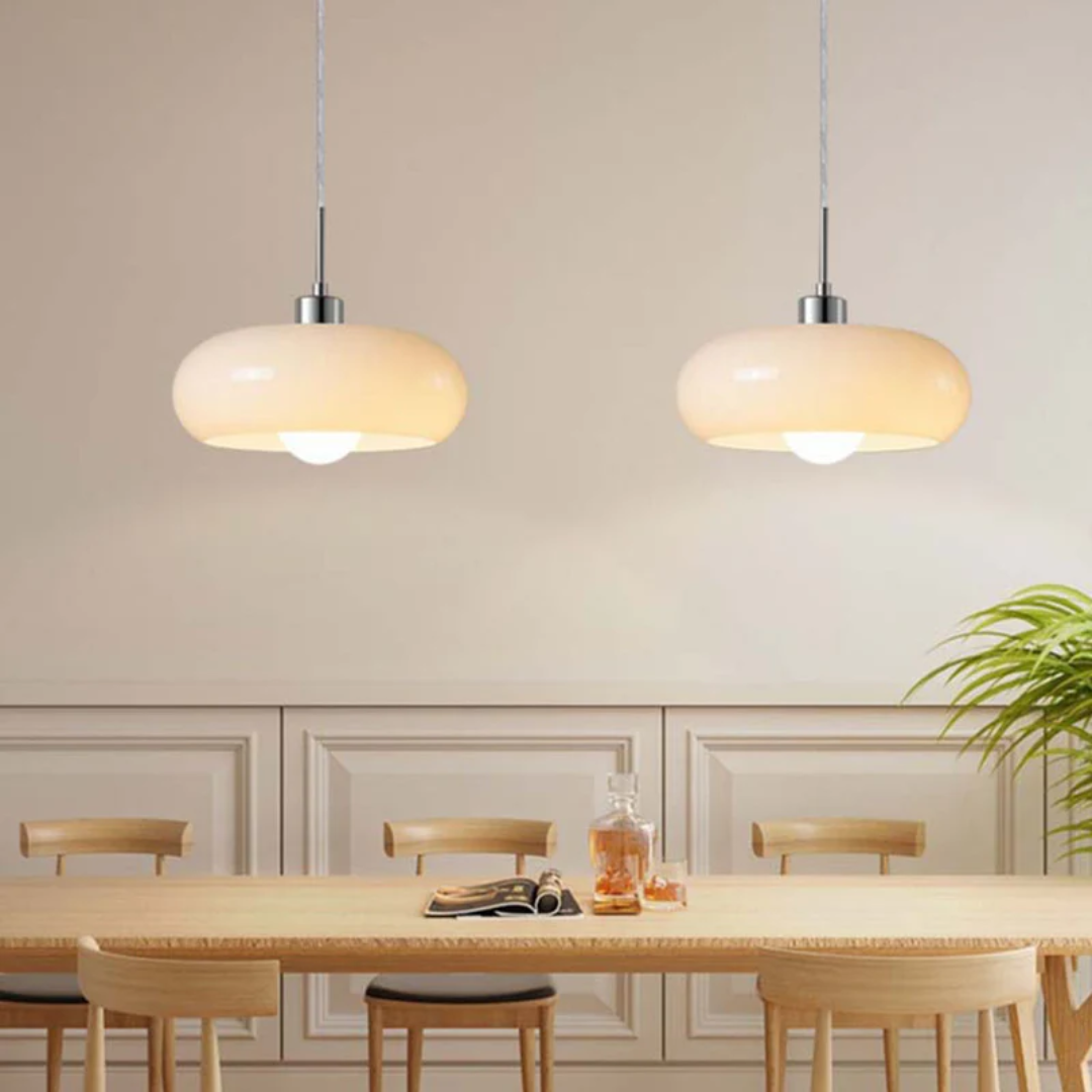 Zwei moderne, beige Pendelleuchten über Esstisch, skandinavisches Design, Holzstühle, Innenraum.