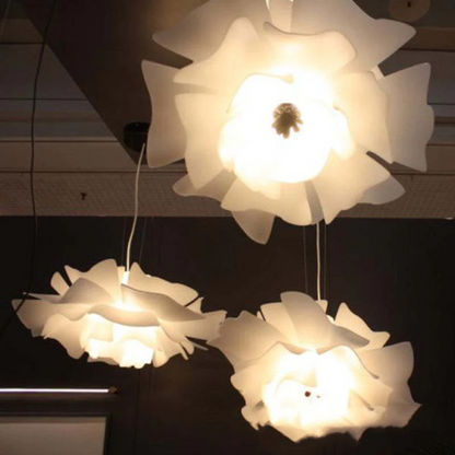Drei weiße, blumenförmige Deckenleuchten aus Kunststoff, modern, hängend, beleuchtet.