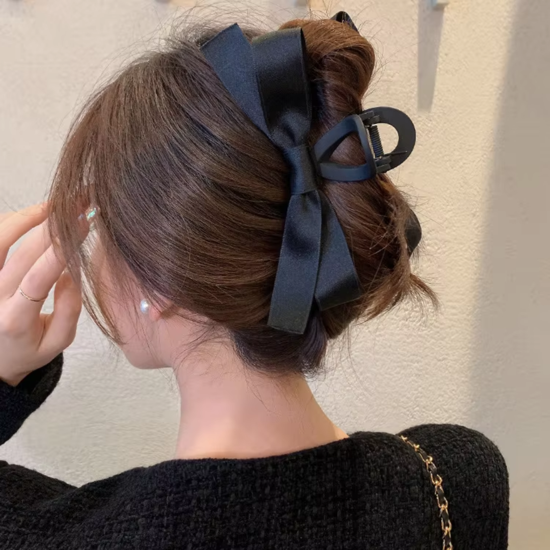 Frau mit schwarzer Haarklammer und Schleife, eleganter Haarstil, modisches Accessoire.