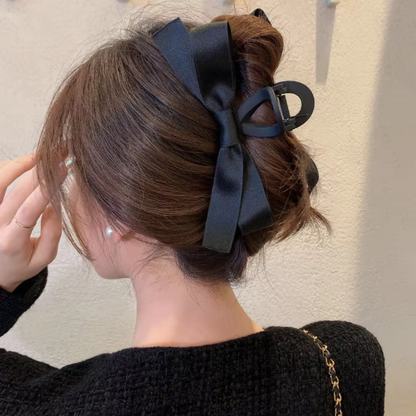 Frau mit schwarzer Haarklammer und Schleife, eleganter Haarstil, modisches Accessoire.