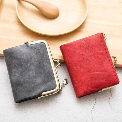 Zwei Vintage-Kisslock-Geldbörsen aus Leder, rot und grau, auf Holztablett.