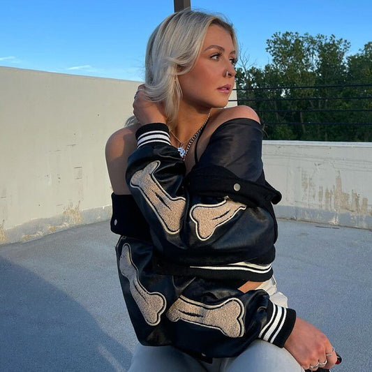 Frau in schwarzer Oversized-Baseballjacke mit Knochenmuster, modisch, lässig, urban.