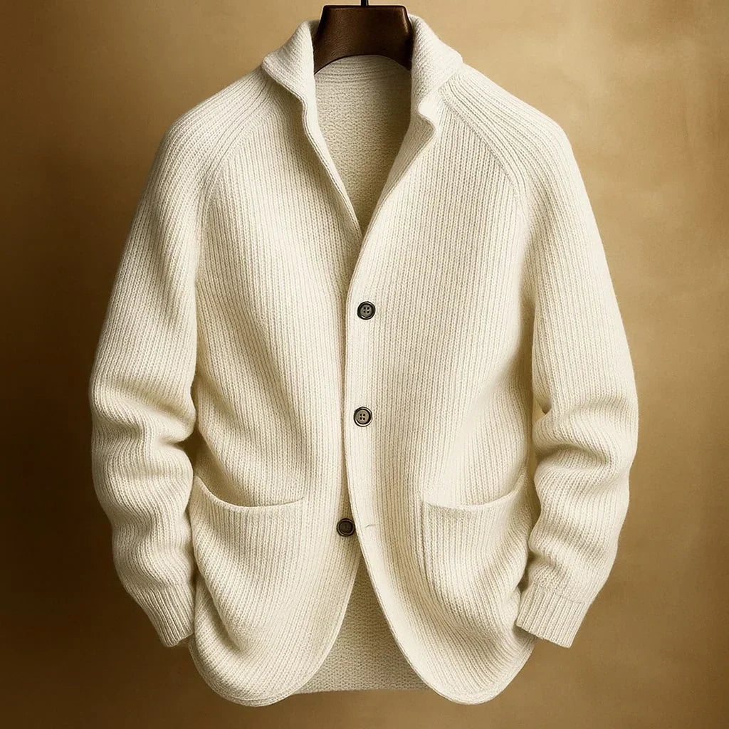 Cremeweiße Strickjacke mit Rippenstruktur und Schalkragen, an Holzbügel vor goldbraunem Hintergrund 2