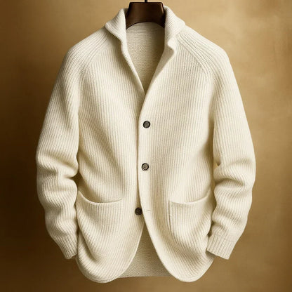 Cremeweiße Strickjacke mit Rippenstruktur und Schalkragen, an Holzbügel vor goldbraunem Hintergrund 2