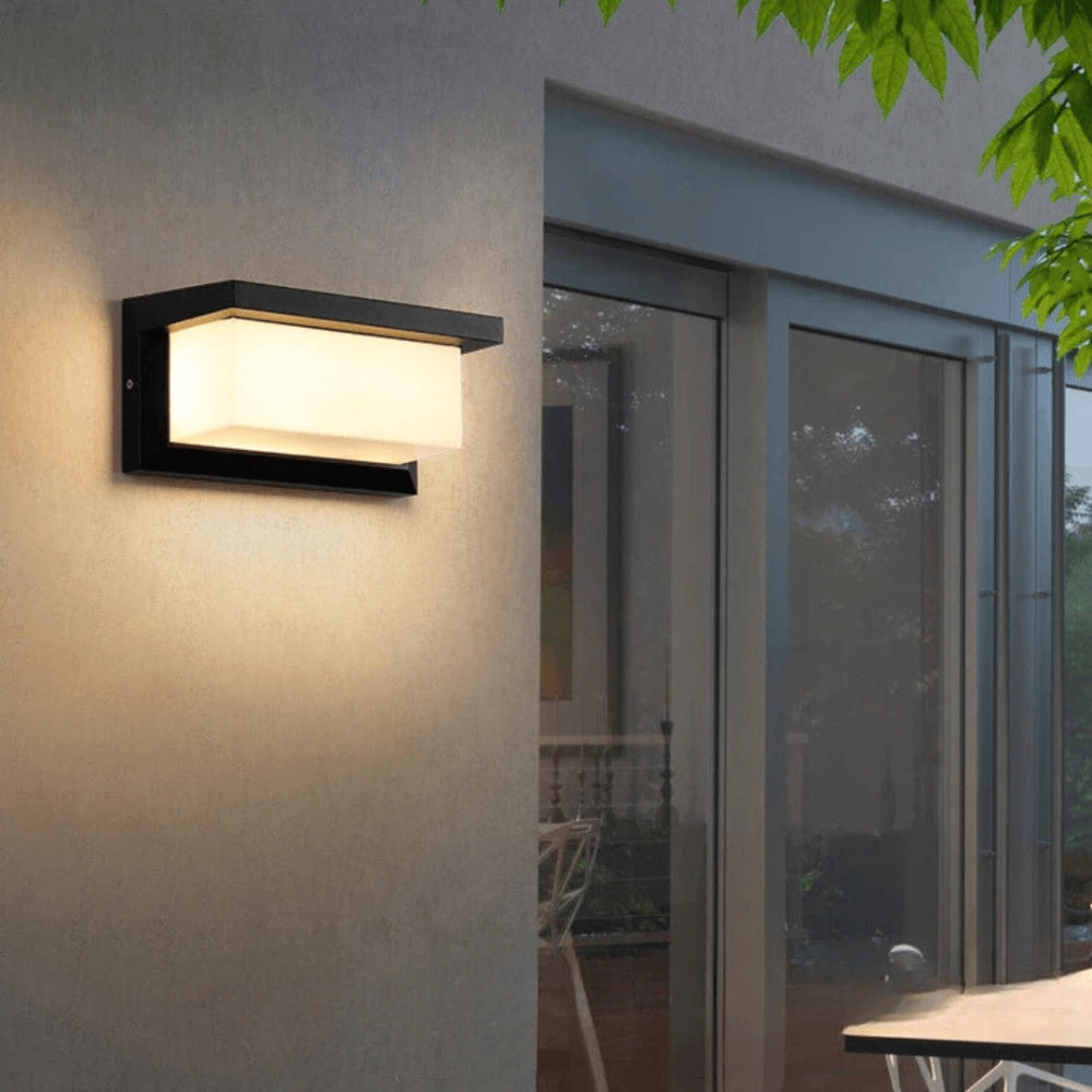 Leuchtende schwarze Wandlampe an einer Putzfassade neben bodentiefen Fenstern am Abend 1