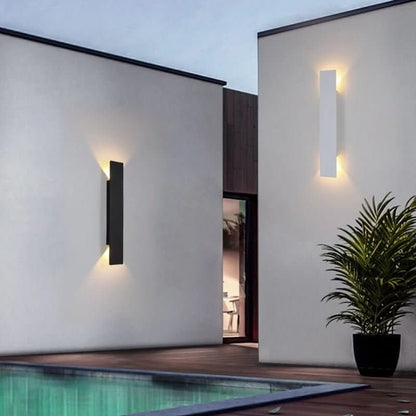 Eine schwarze und eine weiße Wandleuchte an weißen Hauswänden neben einem Pool, mit Topfpflanze im Vordergrund und warmem Auf-und-ab-Licht. 4