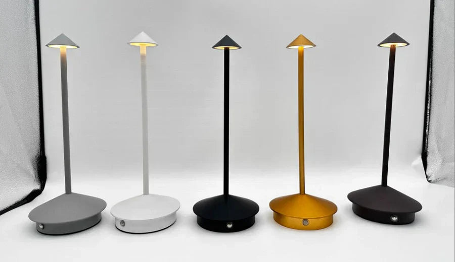 Fünf moderne LED-Tischlampen in Grau, Weiß, Schwarz, Gold und Braun auf weißem Hintergrund.