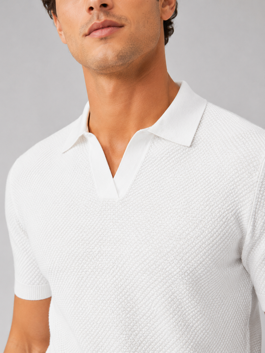 Nahaufnahme des weißen Strickpolos mit Wabenstruktur, V-Ausschnitt und flachem Kragen am Model 31