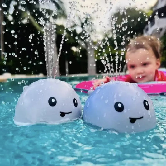Zwei blaue Walspielzeuge im Pool mit spritzendem Wasser, Kind im Hintergrund.