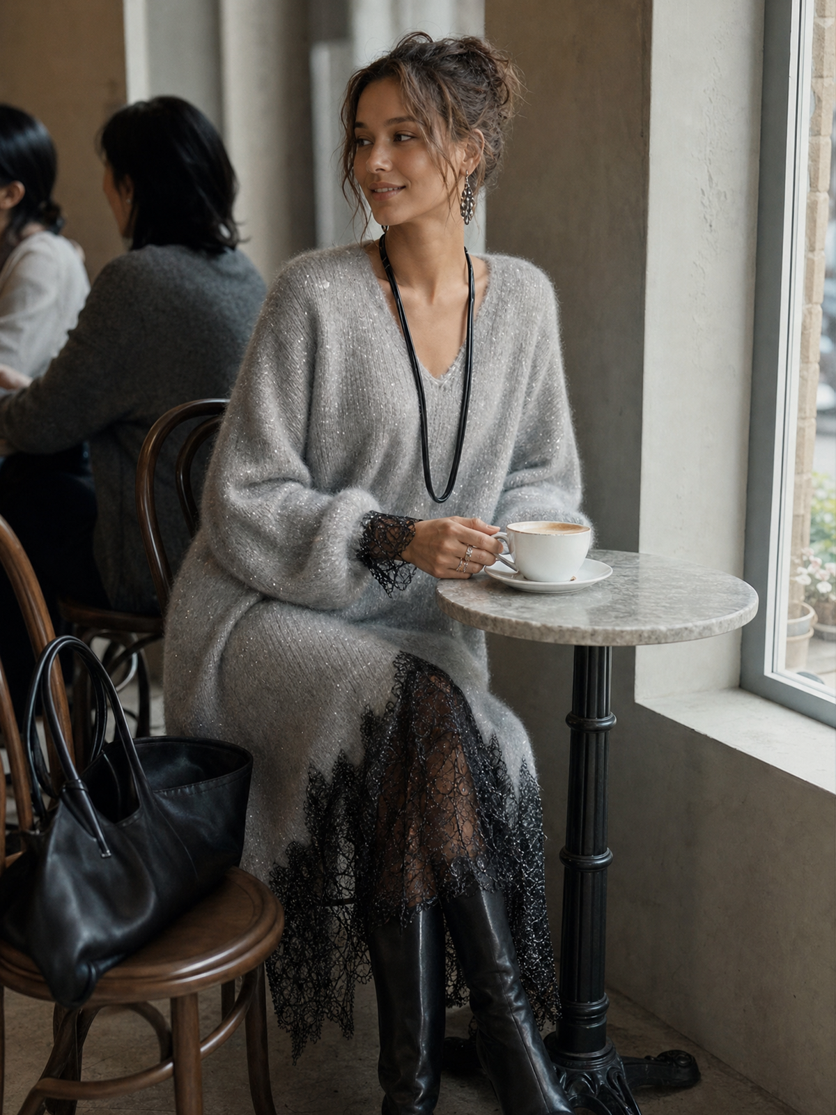 Model sitzt im Café am Marmortisch und trägt das graue Strickkleid mit Spitzenärmelbündchen 4