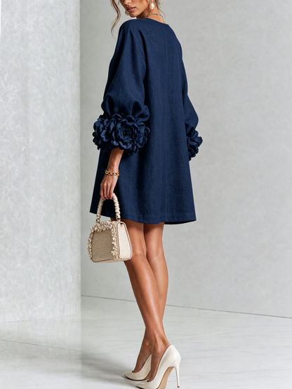Marineblaues Minikleid in der Rückansicht mit Rosenmanschetten an den Ärmeln, Model blickt über die Schulter. 13