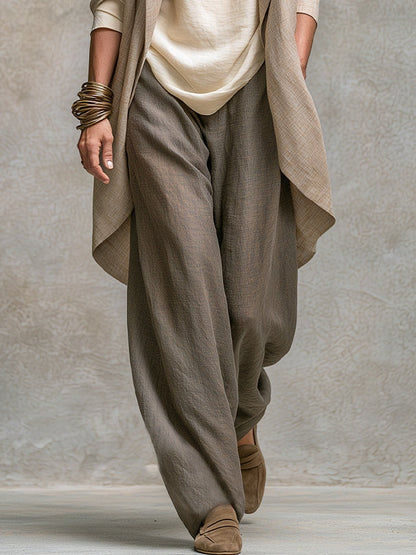 Detailansicht der weiten graubraunen Hose mit lockerem Fall, dazu Jackett-Saum, Oberteil-Saum und Wildleder-Slipper. 5