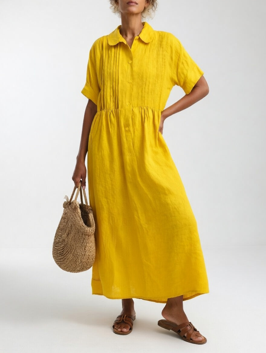 Gelbes Maxikleid mit weitem Rock und Biesen am Oberteil, Frontansicht, eine Hand in der Hüfte, Korbtasche in der anderen. 6