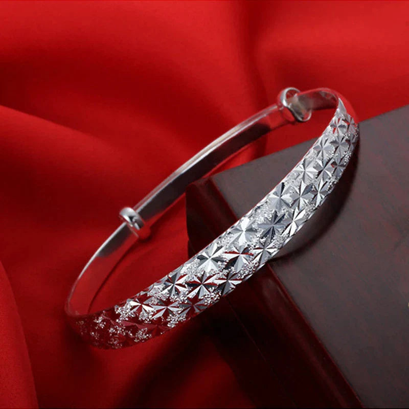 Silberne Damenarmband mit Sternenmuster, modisches Schmuckaccessoire, Geschenkidee.